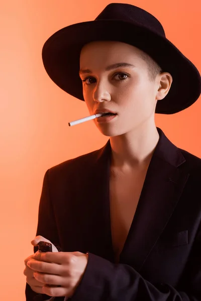 Mulher na moda com cigarro e isqueiro olhando para a câmera no fundo de coral — Fotografia de Stock
