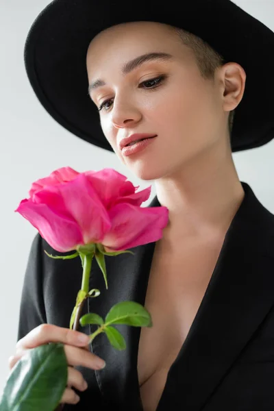 Sensual young woman with perfect skin and natural makeup holding fresh rose isolated on grey — Stock Photo