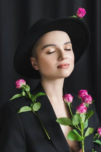 Pretty woman with natural makeup, closed eyes and pink tiny roses on black — Stock Photo