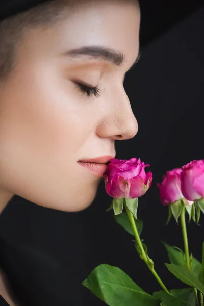 Nahaufnahme des weiblichen Profils in der Nähe von rosa winzigen Rosen isoliert auf schwarz — Stockfoto