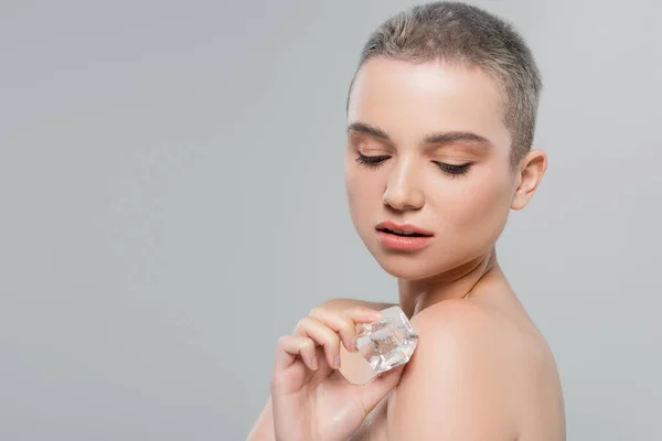 Charming woman with perfect skin holding ice cube near bare shoulder isolated on grey — Stock Photo