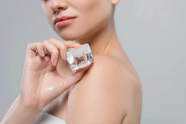 Close up view of ice cube in hand of cropped woman isolated on grey — Stock Photo