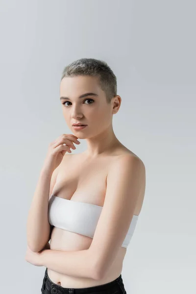 Woman in white top, with bare shoulders, looking at camera isolated on grey — Stock Photo