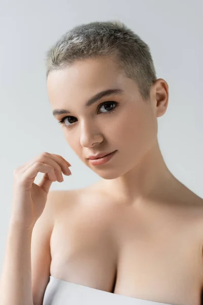 Frau mit sauberer Haut und natürlichem Make-up schaut in Kamera isoliert auf grau — Stockfoto