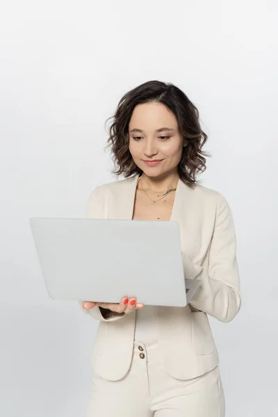 Geschäftsfrau benutzt Laptop, während sie isoliert auf grau steht — Stockfoto