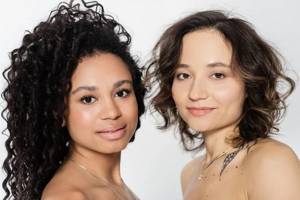 Interracial women with naked shoulders looking at camera isolated on grey, feminism concept — Stock Photo