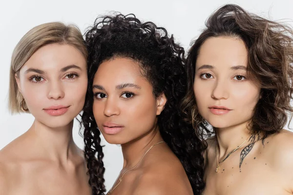 Jeunes femmes multiethniques aux épaules nues regardant la caméra isolée sur gris — Photo de stock