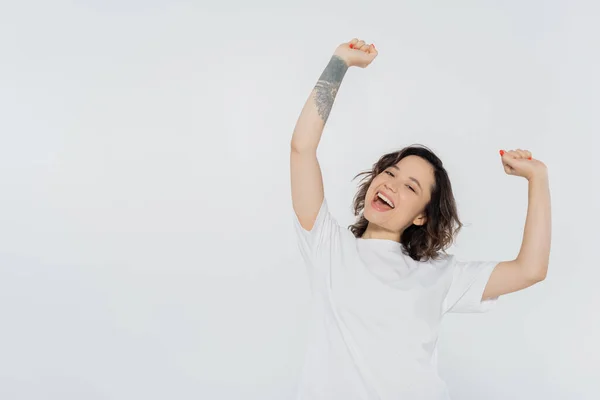 Femme brune joyeuse montrant oui geste isolé sur gris, concept de féminisme — Photo de stock