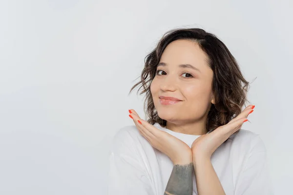 Positive brunette woman looking at camera isolated on grey — Stock Photo