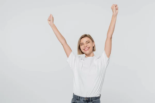 Aufgeregte blonde Frau im weißen T-Shirt zeigt Ja-Geste isoliert auf grau — Stockfoto