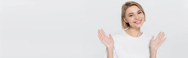 Positive blonde Frau in weißem T-Shirt, Hände winkend auf grauem Banner — Stockfoto