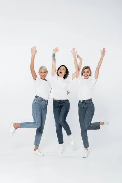 Positive women in jeans and t-shirts waving hands on grey background — Stock Photo