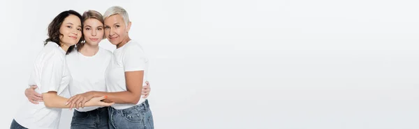 Cheerful women in white t-shirts hugging isolated on grey, banner — Stock Photo