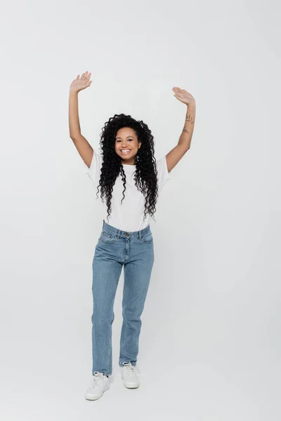 Cheerful tattooed african american woman waving hands on grey background — Stock Photo