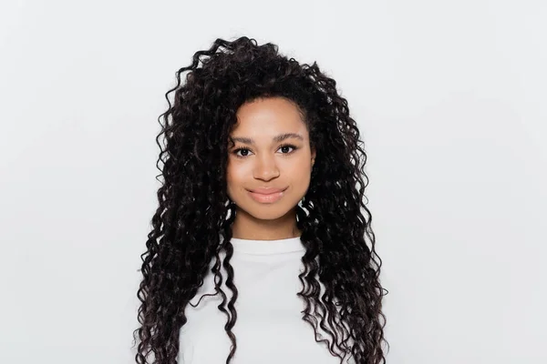 Femme afro-américaine bouclée en t-shirt blanc regardant la caméra isolée sur gris — Photo de stock