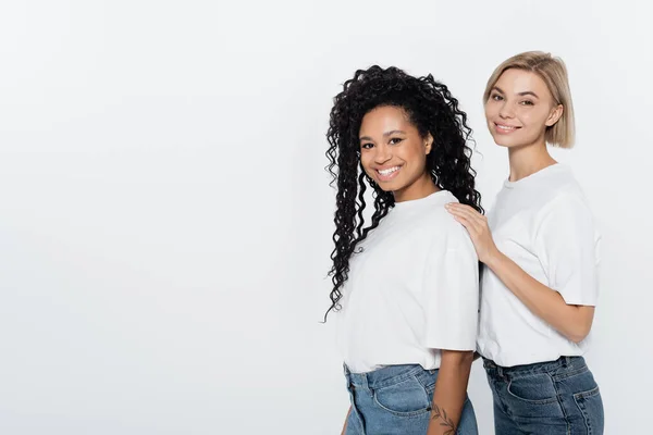 Smiling woman hugging african american friend isolated on grey, feminism concept — Stock Photo