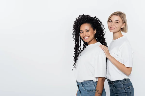 Donna sorridente abbracciando amico afro-americano isolato sul grigio, concetto di femminismo — Foto stock