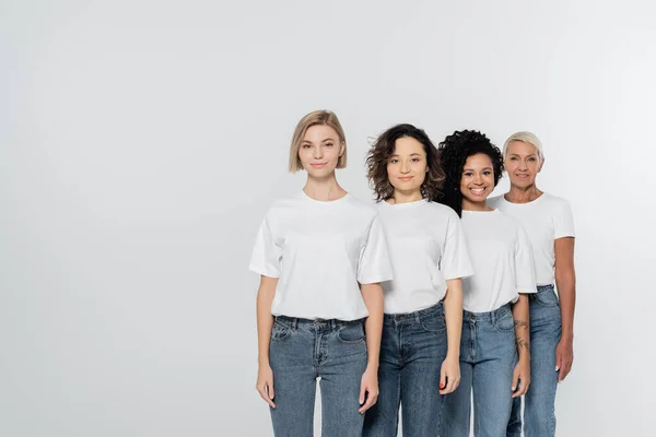 Positive multiethnic women smiling at camera isolated on grey — Stock Photo