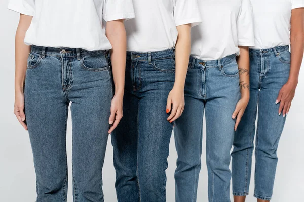 Cropped view of interracial women in jeans and t-shirts isolated on grey — Stock Photo