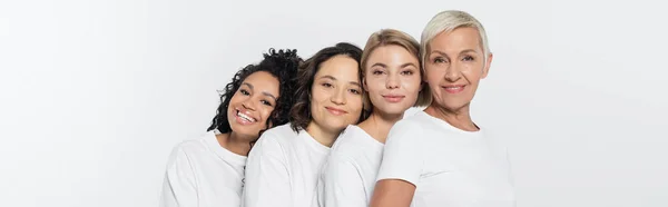 Multiethnische Frauen in weißen T-Shirts blicken vereinzelt in die Kamera auf grauem Banner — Stockfoto