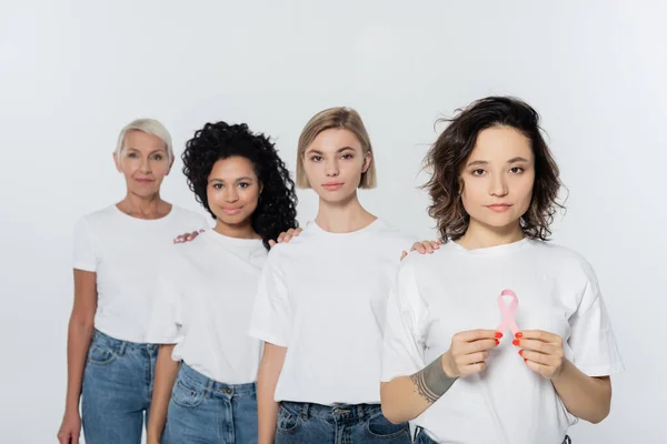 Татуйована жінка тримає стрічку поінформованості про рак молочної залози біля міжрасових друзів ізольовано на сірому — стокове фото