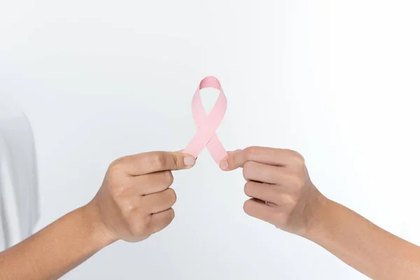 Cropped view of women holding pink ribbon of breast cancer awareness isolated on grey — Stock Photo