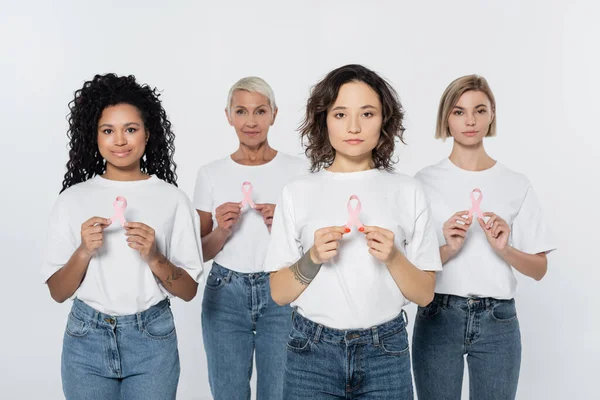 Woman holding pink ribbon of breast cancer awareness near interracial friends isolated on grey — Stock Photo