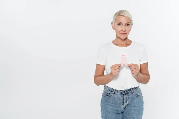 Mujer mayor sosteniendo cinta de conciencia de cáncer de mama aislada en gris - foto de stock