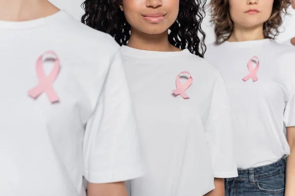 Ausgeschnittene Ansicht einer afrikanisch-amerikanischen Frau mit rosa Schleife auf T-Shirt, die in der Nähe von Freunden isoliert auf grau steht — Stockfoto