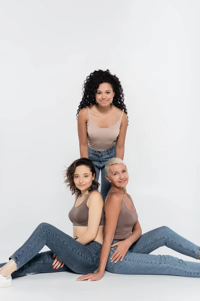 Curly african american woman standing near friends on grey background — Stock Photo