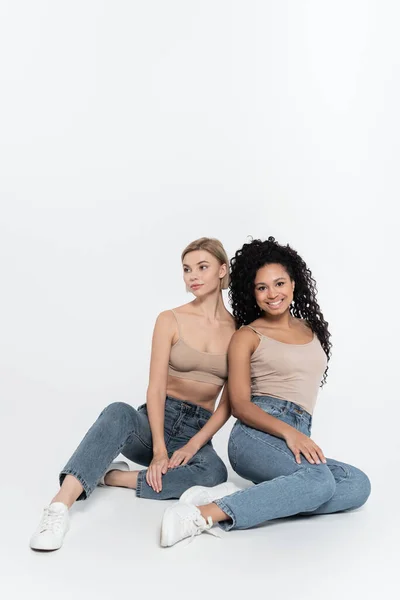 Smiling african american woman sitting near friend on grey background, feminism concept — Stock Photo