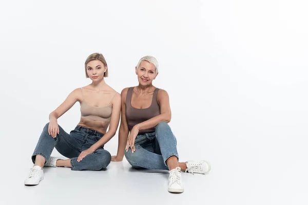 Seniorin lächelt neben junger Freundin auf grauem Hintergrund, Feminismus-Konzept — Stockfoto