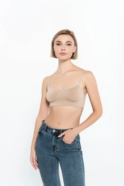 Femme blonde en haut tenant la main dans la poche de jeans isolés sur gris — Photo de stock