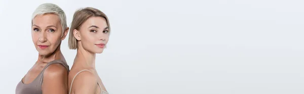 Blonde woman standing back to back with friend isolated on grey, banner — Stock Photo