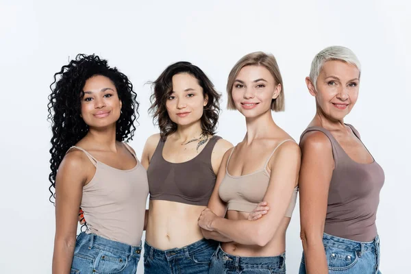 Femmes interraciales positives en haut regardant la caméra isolée sur gris, concept féministe — Photo de stock