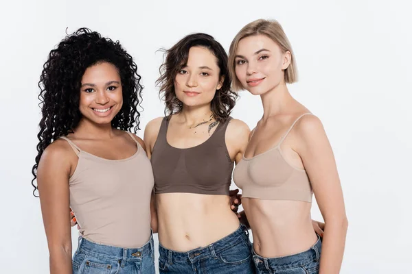 Young woman in top hugging interracial friends isolated on grey — Stock Photo