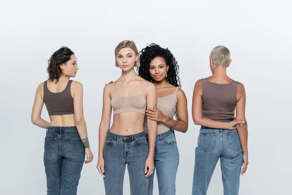 Multiethnische Frauen in Tops posieren auf grauem Hintergrund — Stockfoto