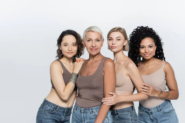 Donne multietniche che si abbracciano e sorridono alla telecamera isolata su grigio — Foto stock