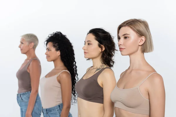 Blonde woman standing near blurred multiethnic friends isolated on grey — Stock Photo