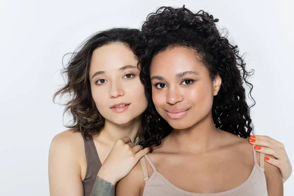 Jeune femme brune embrassant une amie afro-américaine isolée sur du gris, concept féministe — Photo de stock