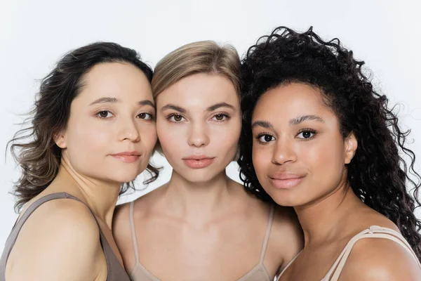 Mujeres jóvenes multiétnicas mirando a la cámara aisladas en gris, concepto de feminismo - foto de stock