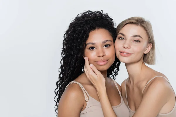 Femme blonde souriante touchant le visage d'un ami afro-américain isolé sur du gris — Photo de stock