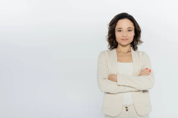 Brünette Geschäftsfrau in formeller Kleidung, die Arme verschränkt auf grau, Feminismus-Konzept isoliert — Stockfoto