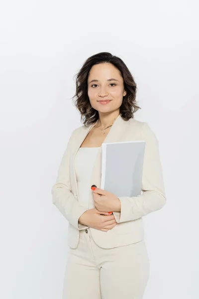 Positive businesswoman in suit holding paper folder isolated on grey — Stock Photo