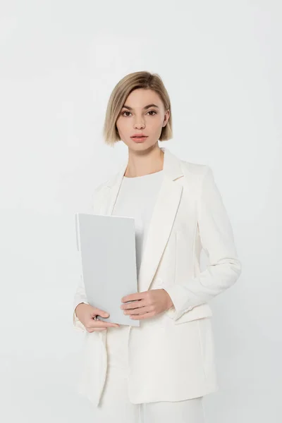 Блондинка-бизнесвумен в костюме держит бумажную папку изолированную на сером — стоковое фото