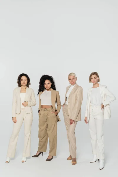 Multiethnic businesswomen posing and looking at camera on grey background — Stock Photo