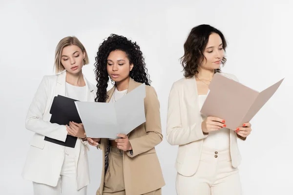 Donne d'affari interrazziali in possesso di cartelle di carta vicino collega isolato su grigio — Foto stock