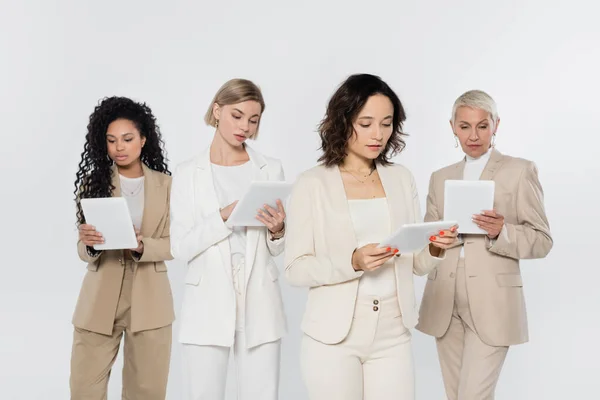 Empresaria usando tableta digital cerca de colegas multiétnicos aislados en gris — Stock Photo