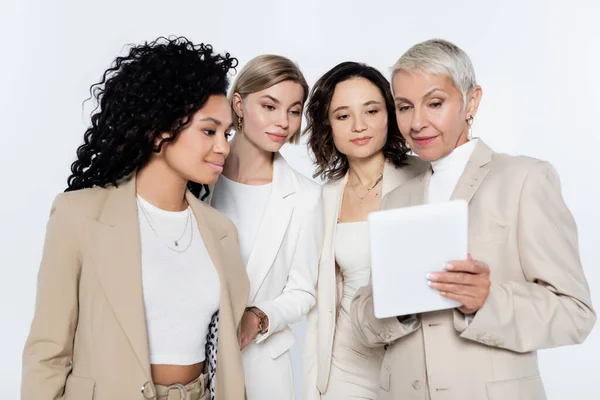 Senior businesswoman using digital tablet near interracial colleagues isolated on grey — Stock Photo