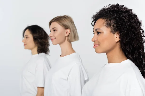 Sorridente donna afro-americana in piedi vicino ad amici offuscati isolati sul grigio — Foto stock